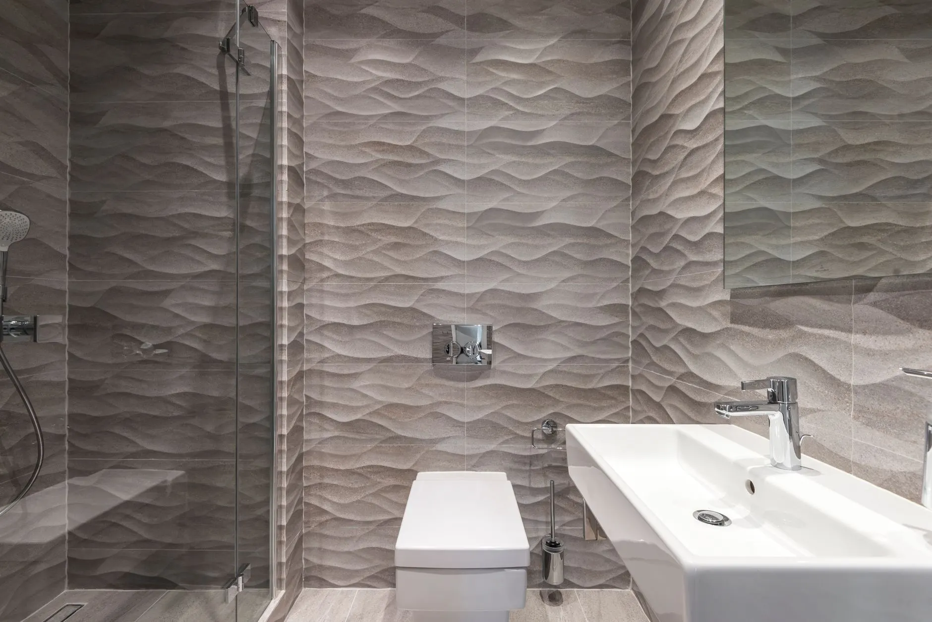 Sleek bathroom featuring textured walls, a glass shower, and a modern sink.