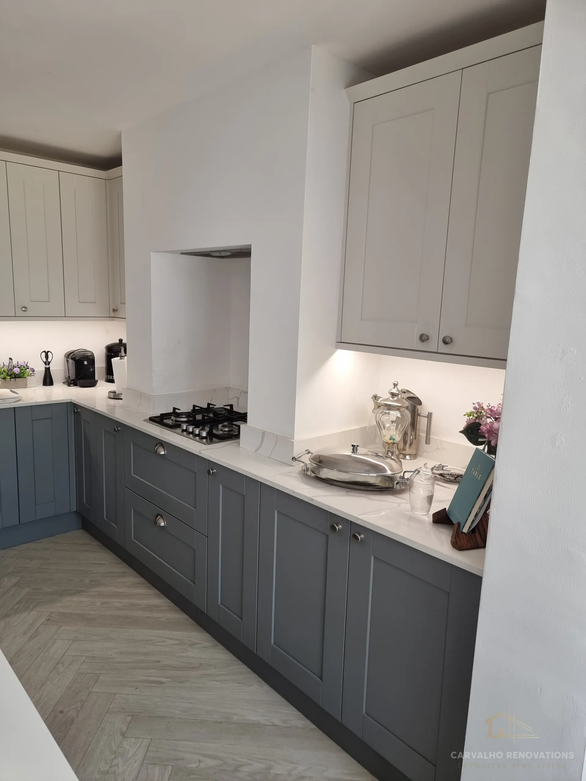 Dark grey base units with a gas hob set into a marble-effect worktop and upstand, and an extractor recessed into the chimney breast.